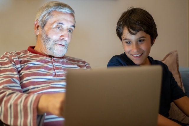 Older adult and young boy looking at a laptop.