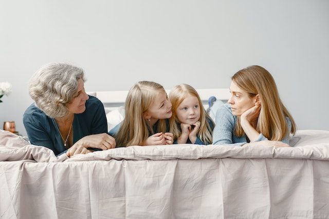Family of three generations sitting together on a bed.