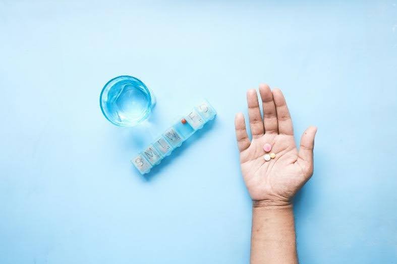 unnamed (4) A hand next to a medication container.